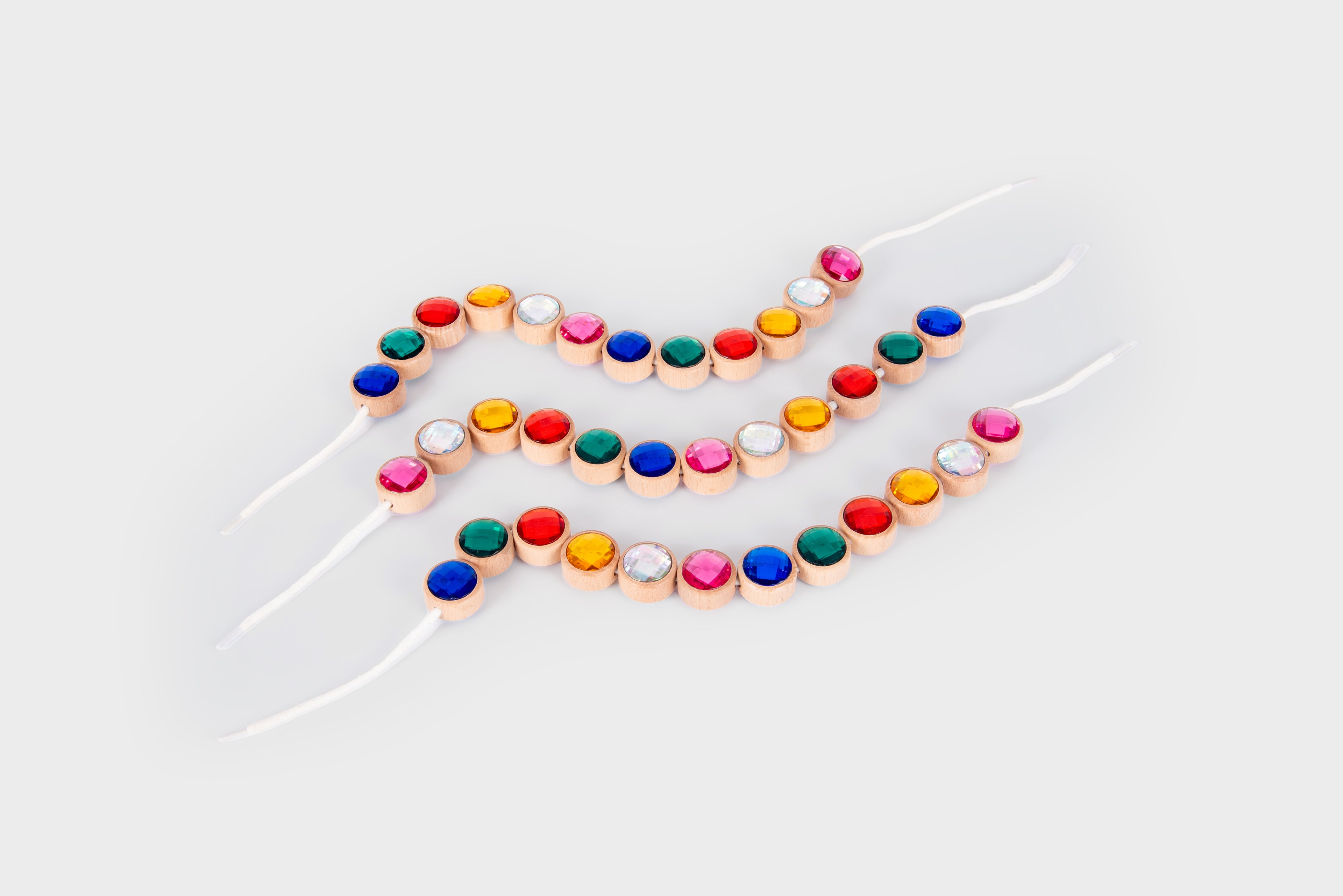 Wooden lacing jewels set with multicolor round beads on white string ties