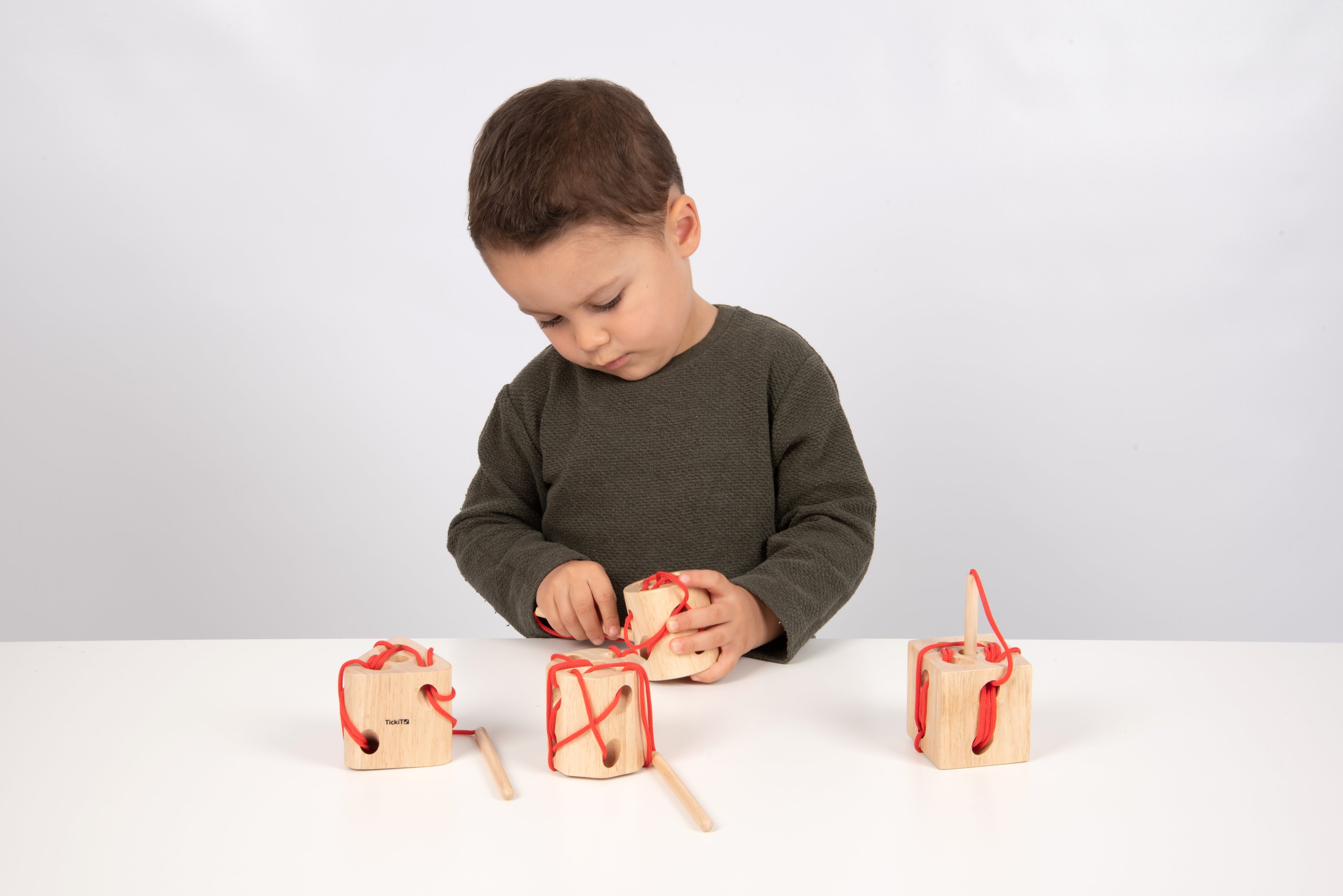 Wooden lacing blocks with red laces and dowel tools, child stitching through holes