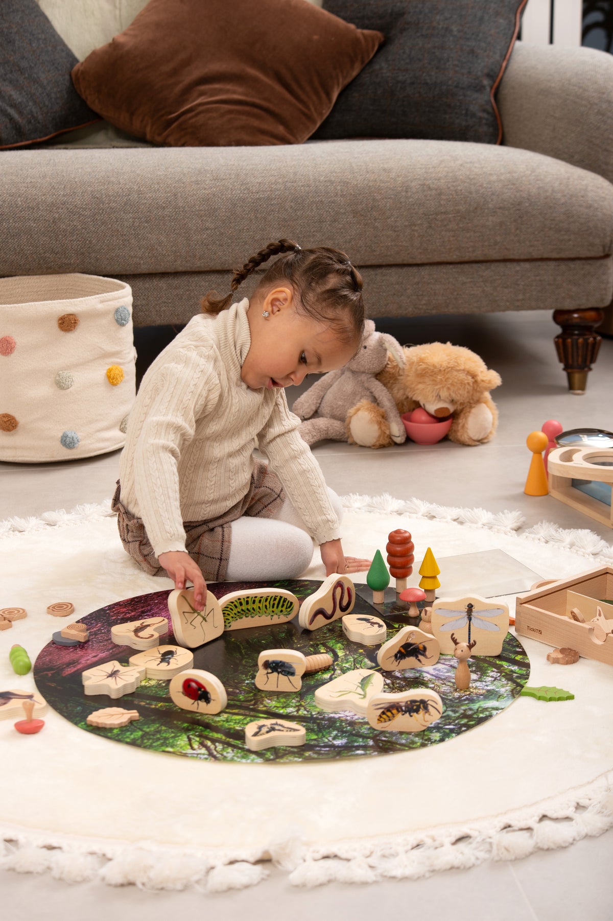 Wooden minibeast blocks scattered on a round play mat, featuring painted bug designs