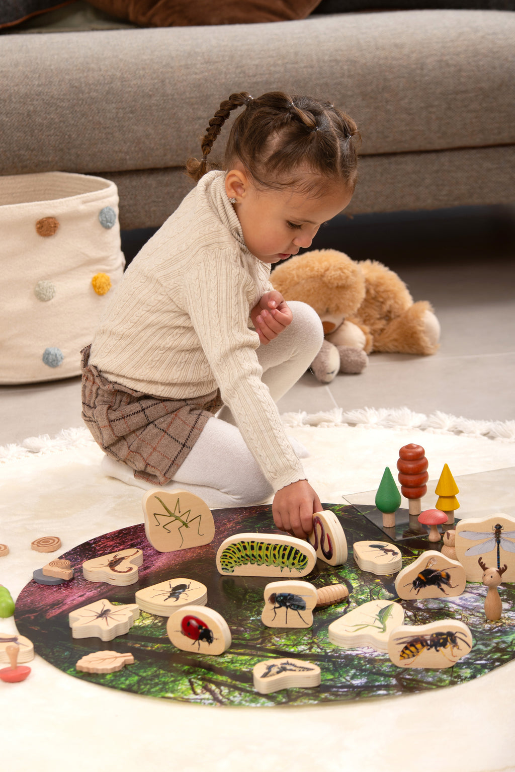 Wooden minibeast blocks on a play mat, showing painted beetles, bugs, and worms
