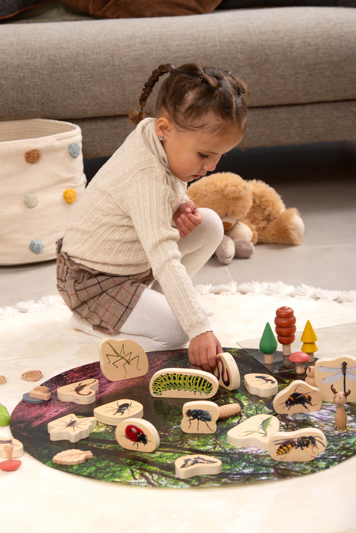 Wooden minibeast blocks on a play mat, showing painted beetles, bugs, and worms