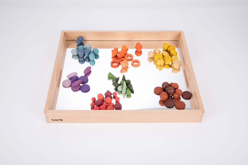 Wooden mirror tray filled with colorful wooden pieces arranged across the reflective base