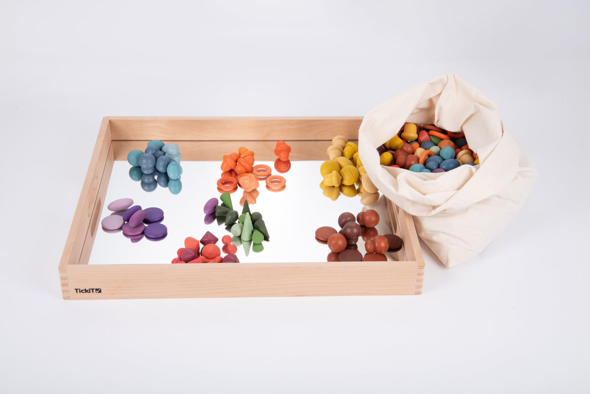 Wooden mirror tray with colorful wooden pieces on the reflective base and a fabric bag