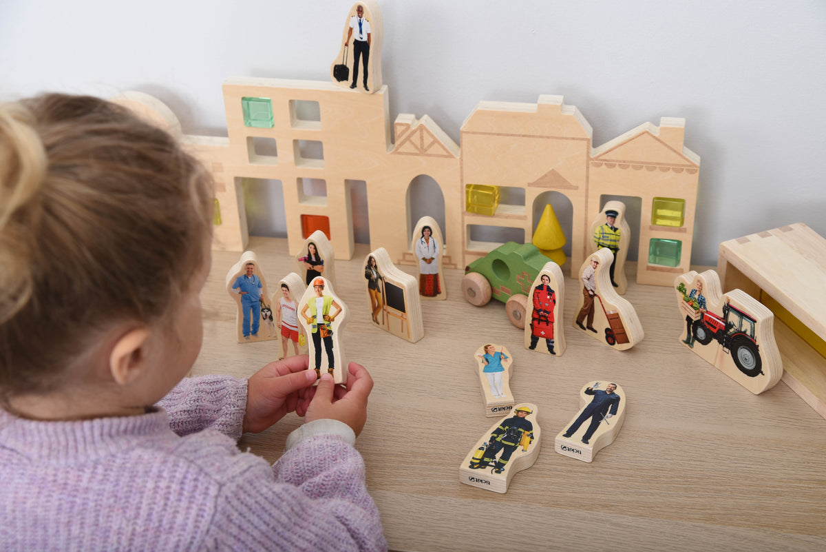 Wooden town playset with people figurines and vehicles, arranged around small buildings