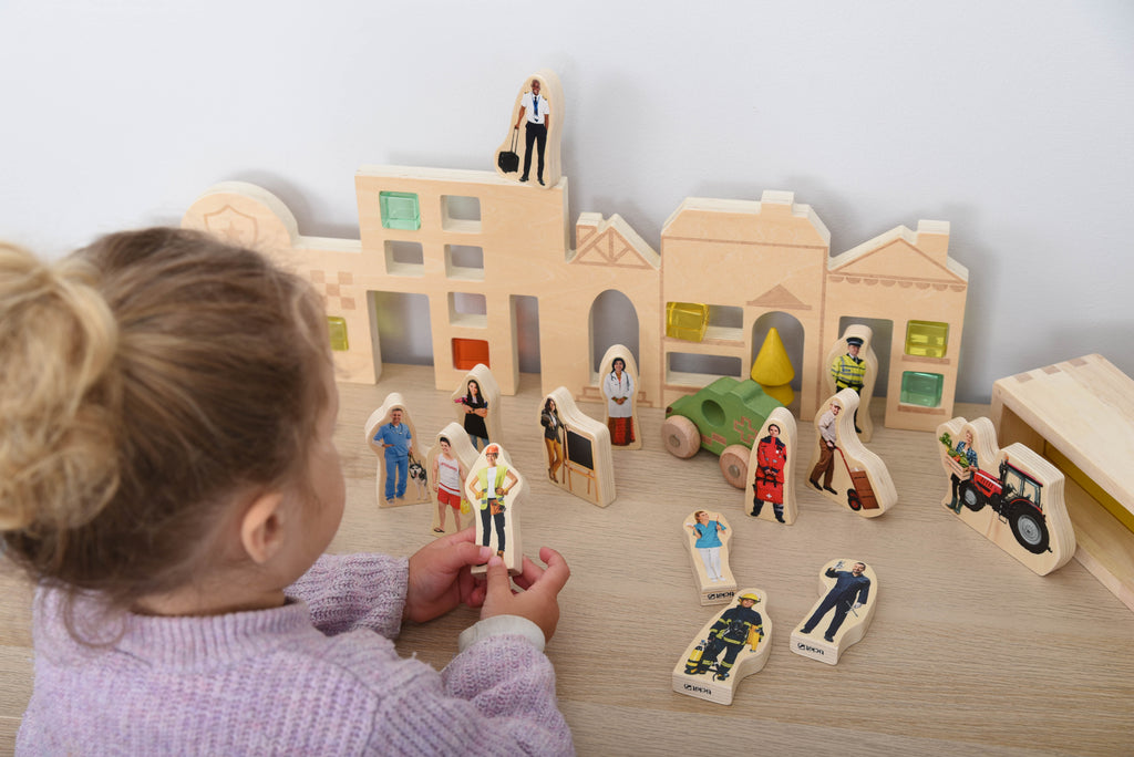 Wooden people figurines on a wooden town playset with house and vehicle blocks