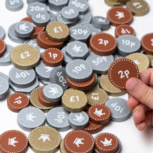 Wooden play money coin set with pence and pound denominations, one coin held by hand