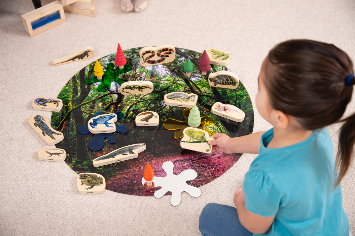 Wooden reptile and amphibian blocks being placed on a round jungle-themed board