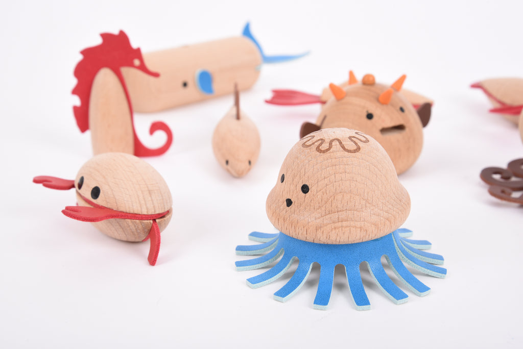 Wooden sea creature figurines: blue whale, red seahorse, orange puffer fish, and jellyfish