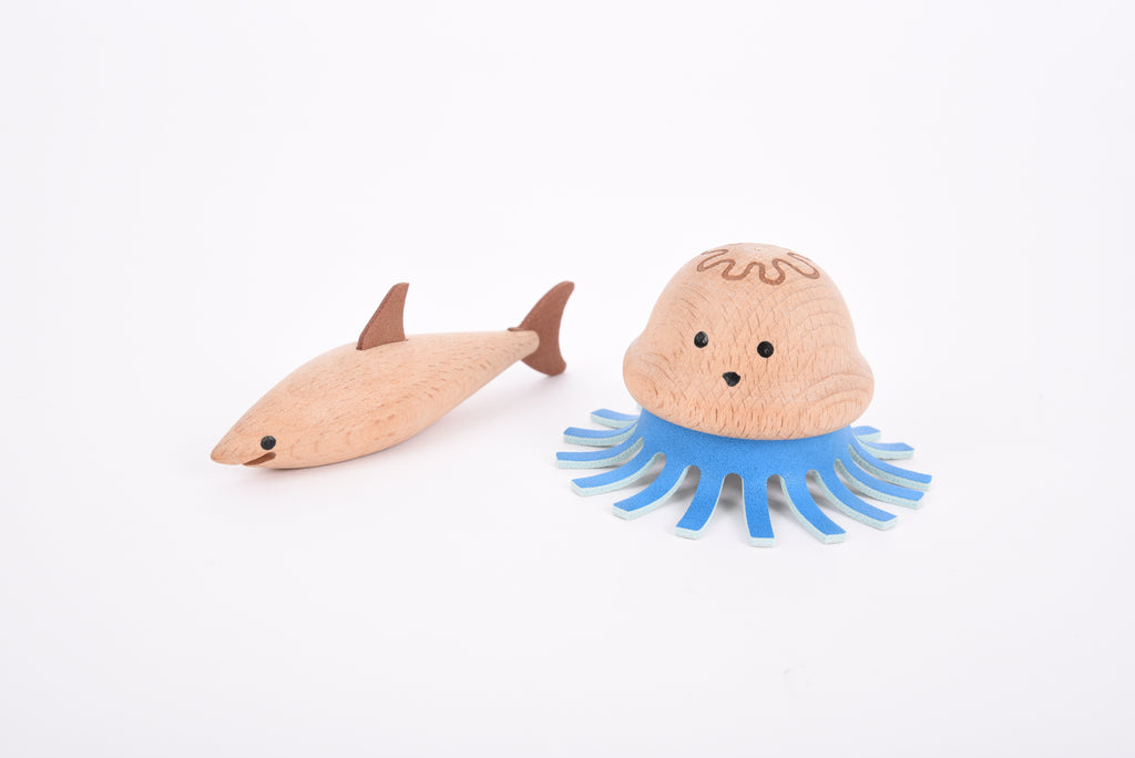 Wooden sea creature figurines close-up: pale fish and blue-outlined jellyfish