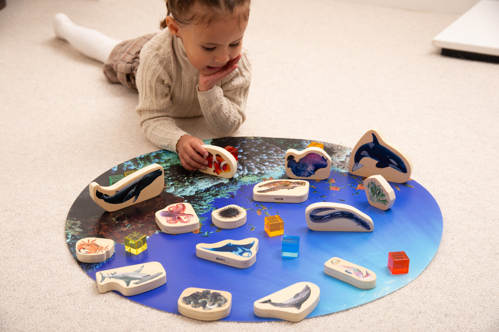 Child reaching to place wooden sea animal blocks with shark and dolphin shapes