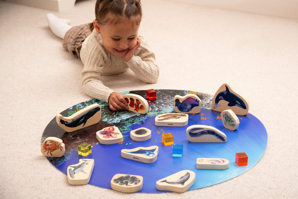 Kid playing with wooden sea animal blocks shaped like dolphins, sharks and fish