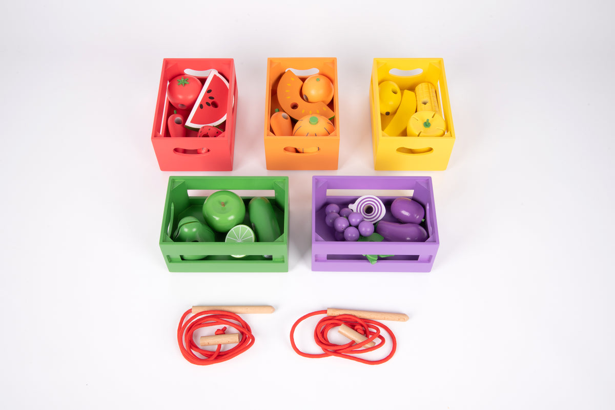 Wooden sorting crates filled with toy produce and red lacing cords with sticks