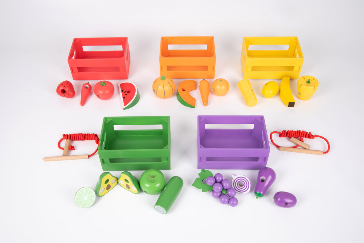 Six rainbow wooden sorting crates with toy fruit and vegetables and red lacing cords