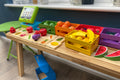 Wooden sorting fruit crates with colorful toy produce on a tabletop