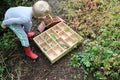 Wooden 14-slot sorting tray with dividers, held outdoors with play items