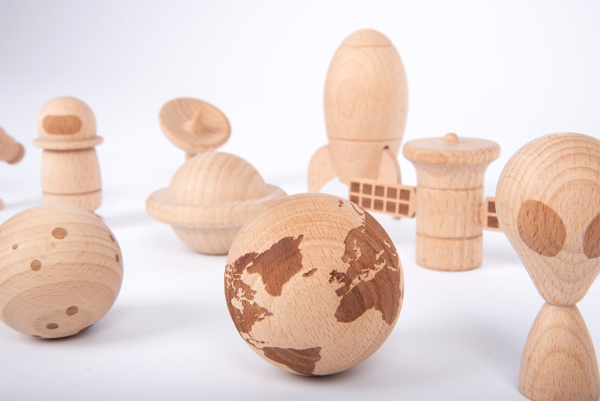 Close view of wooden astronaut, planet sphere and rover pieces in light wood