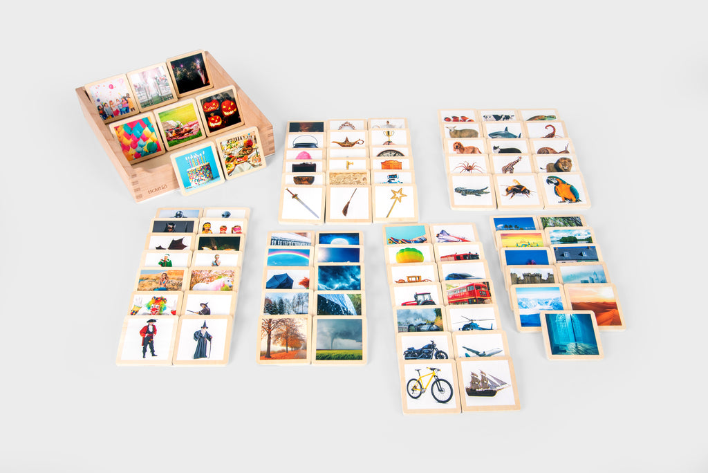 Open wooden story tile box with many photo tiles showing bikes, vehicles, and nature scenes