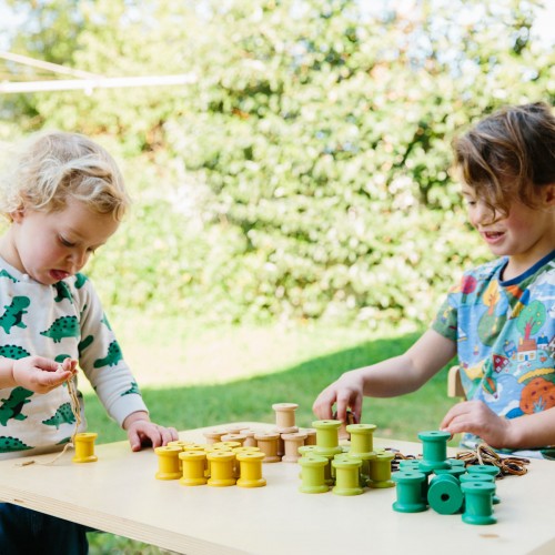 Colorful wooden threading reels with spool shapes in yellow, green, blue