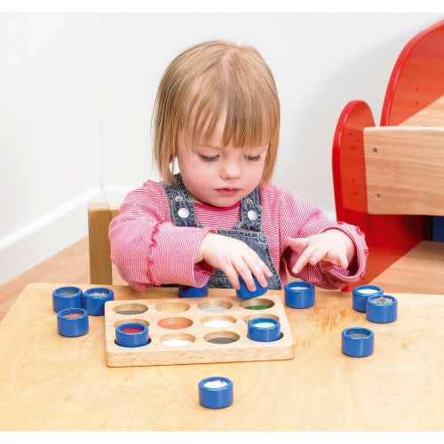 Wooden touch-and-match board with blue rings and textured colored pieces, child playing