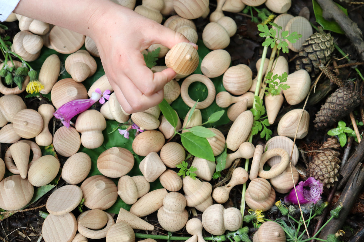 Wooden acorn and leaf pieces with a hand reaching among natural items