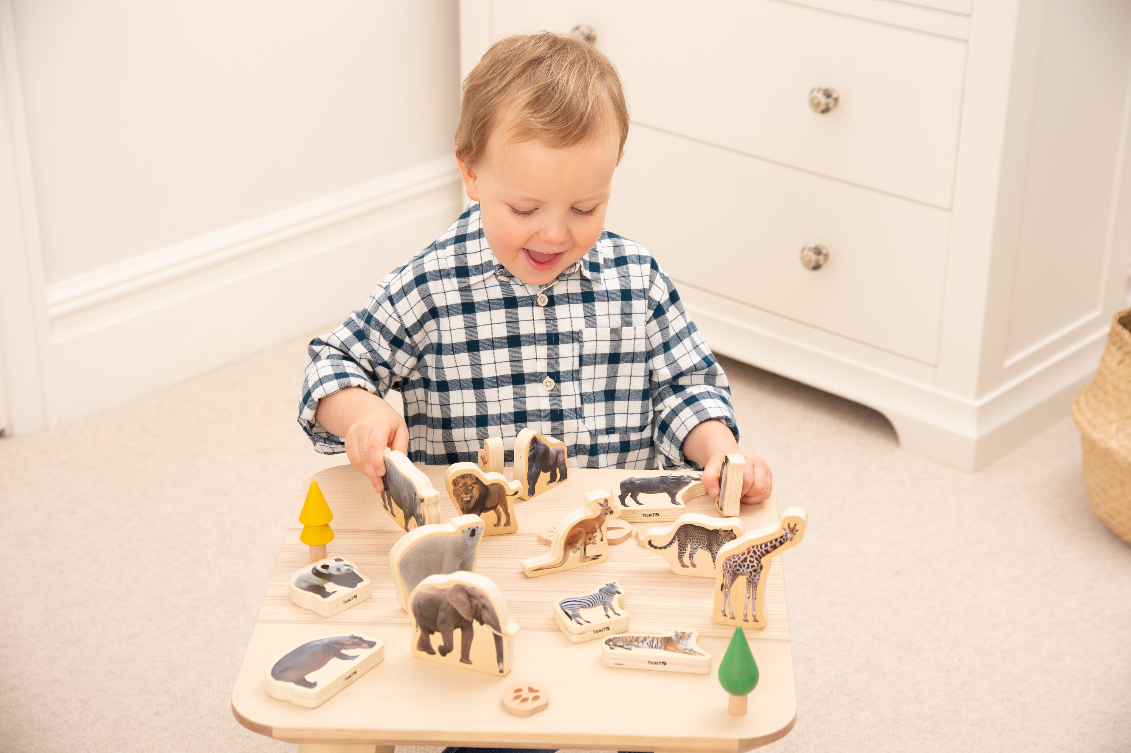 Toddler building with wooden wild animal blocks on a light play tray