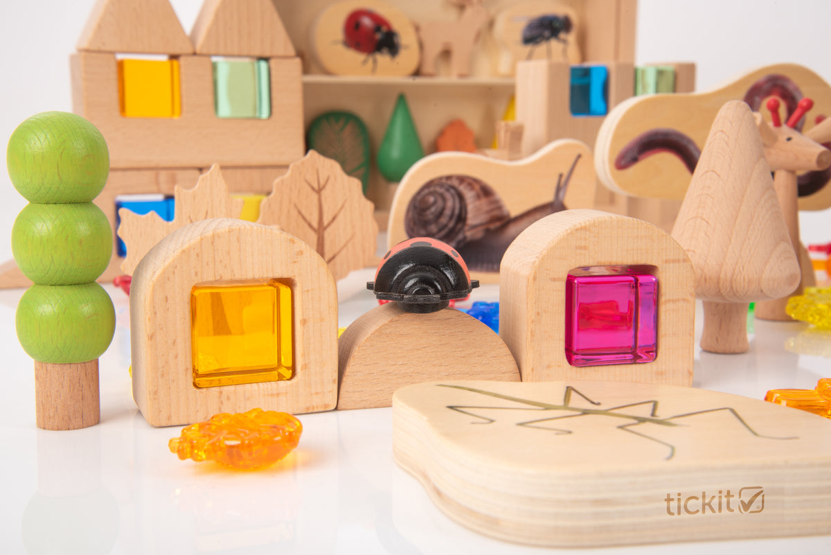 Wooden woodland playset pieces with houses, windows, and stacked tree shapes plus translucent blocks