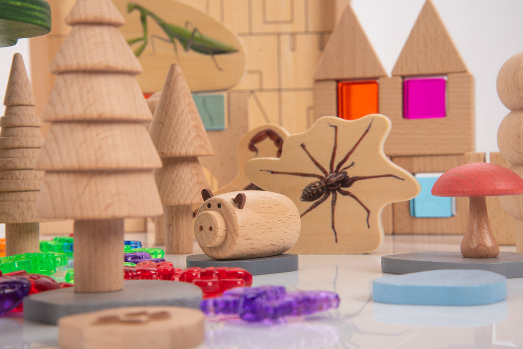 Wooden pig figure, tree blocks, and colorful bead pieces on the woodland playset