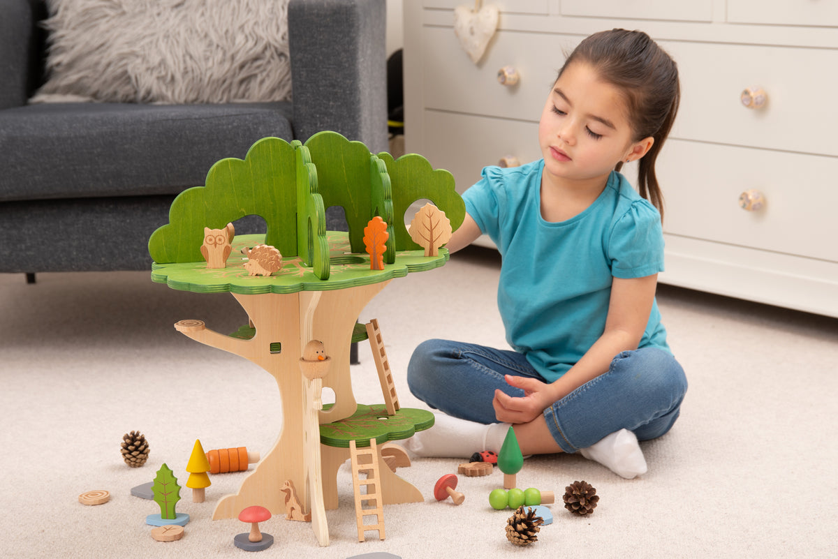 Wooden treehouse playset with green canopy and ladder, with small wooden accessories