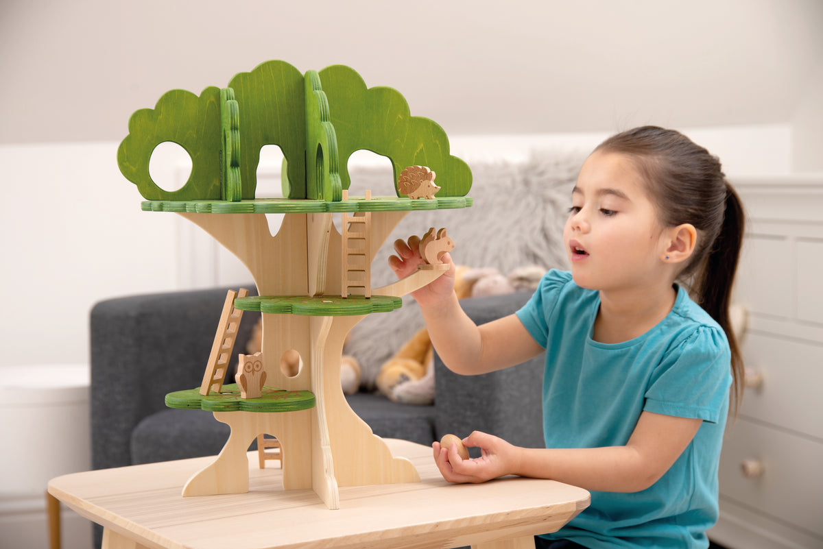 Wooden treehouse playset with green canopy and animal figures on tabletop